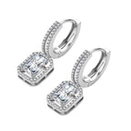 Sterling silver huggie hoops with emerald-cut moissanite drops featuring pavé-set crystals on white background.