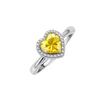 Heart-shaped yellow moissanite ring with diamond halo in sterling silver setting on neutral background