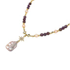 Gold necklace with iridescent baroque pearl pendant, purple amethyst beads, and crystal star charm on cream background