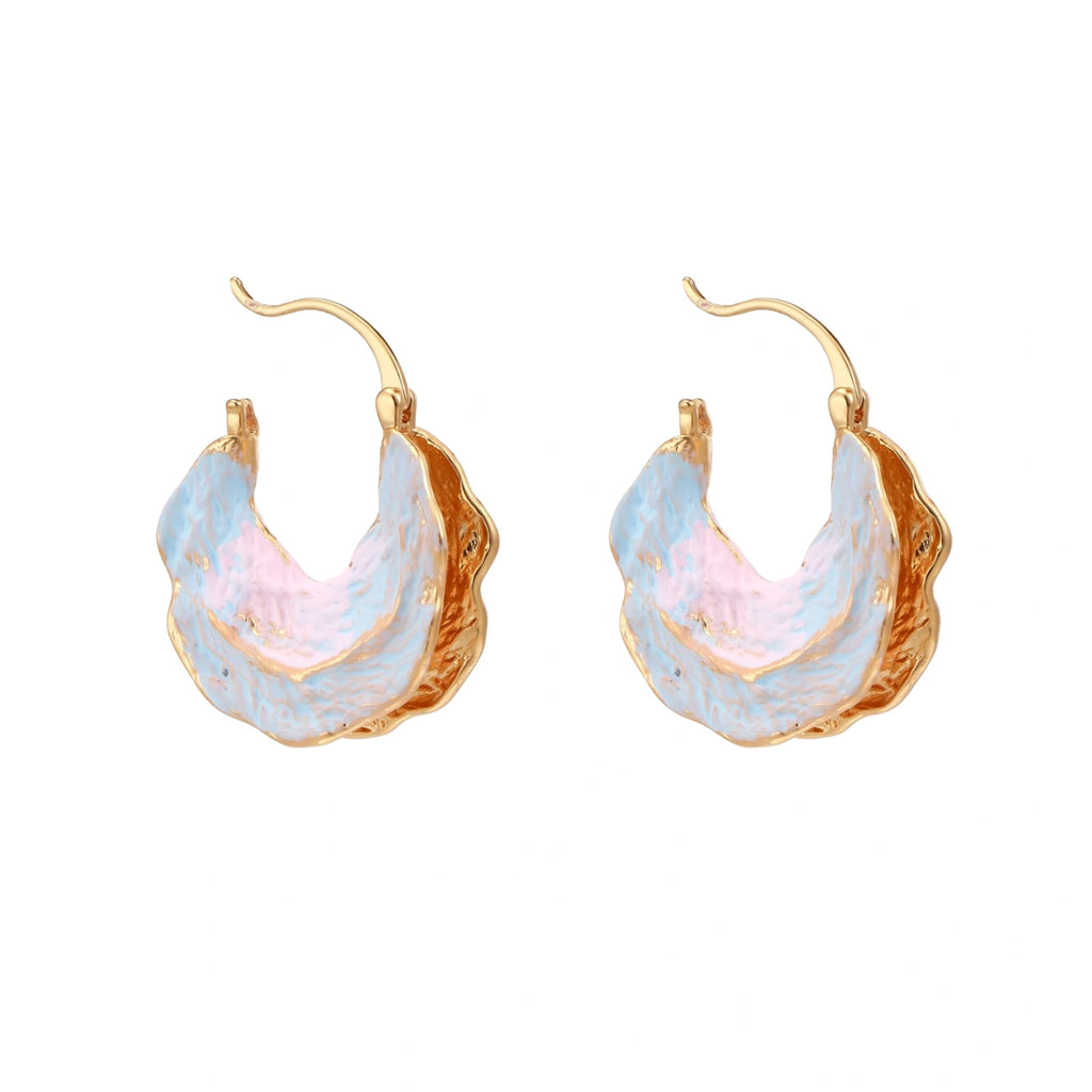 Shell-shaped hoop earrings with iridescent blue-pink enamel and gold trim on cream background