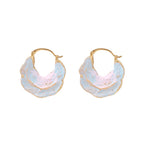 Shell-shaped hoop earrings with iridescent blue-pink enamel and gold trim on cream background
