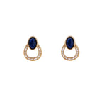 Gold drop earrings with oval lapis lazuli, crystal-paved frame, and iridescent mother-of-pearl teardrop on cream background
