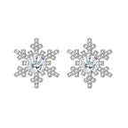 Sterling silver snowflake stud earrings with brilliant moissanite centers and intricate geometric patterns on cream background