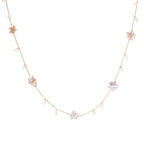 Gold vermeil chain with iridescent star-shaped baroque pearls and small round freshwater pearl drops on cream background.