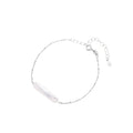 Minimalist bracelet with iridescent baroque pearl on rhodium-plated sterling silver chain against cream background