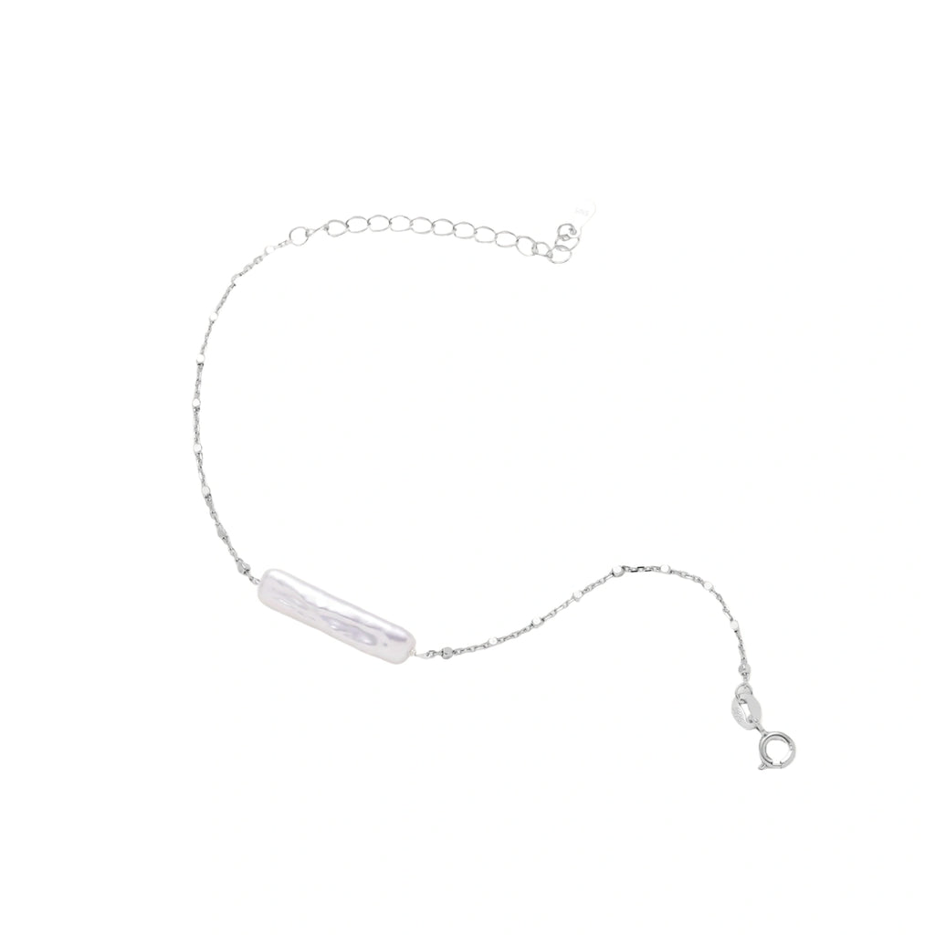 Minimalist bracelet with iridescent baroque pearl on rhodium-plated sterling silver chain against cream background