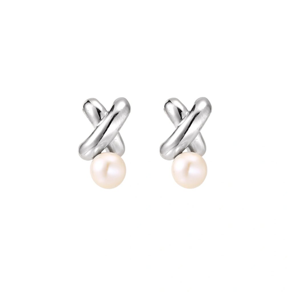 Rhodium-plated silver earrings with twisted X design and freshwater pearl drops on beige background