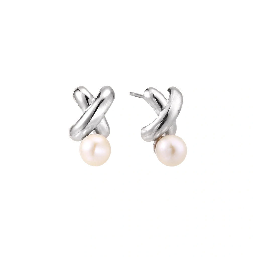 Rhodium-plated silver earrings with twisted X design and freshwater pearl drops on beige background