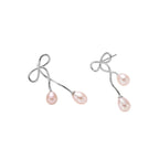 Rhodium-plated silver earrings with organic vine curves and two peachy freshwater pearls on cream background