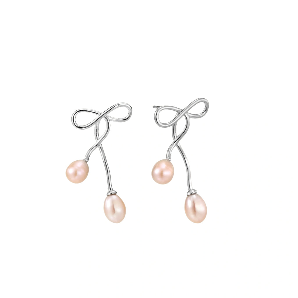 Rhodium-plated silver earrings with organic vine curves and two peachy freshwater pearls on cream background