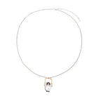 Whimsical owl pendant holding a white pearl on a gold swing, rhodium-plated silver chain on cream background.