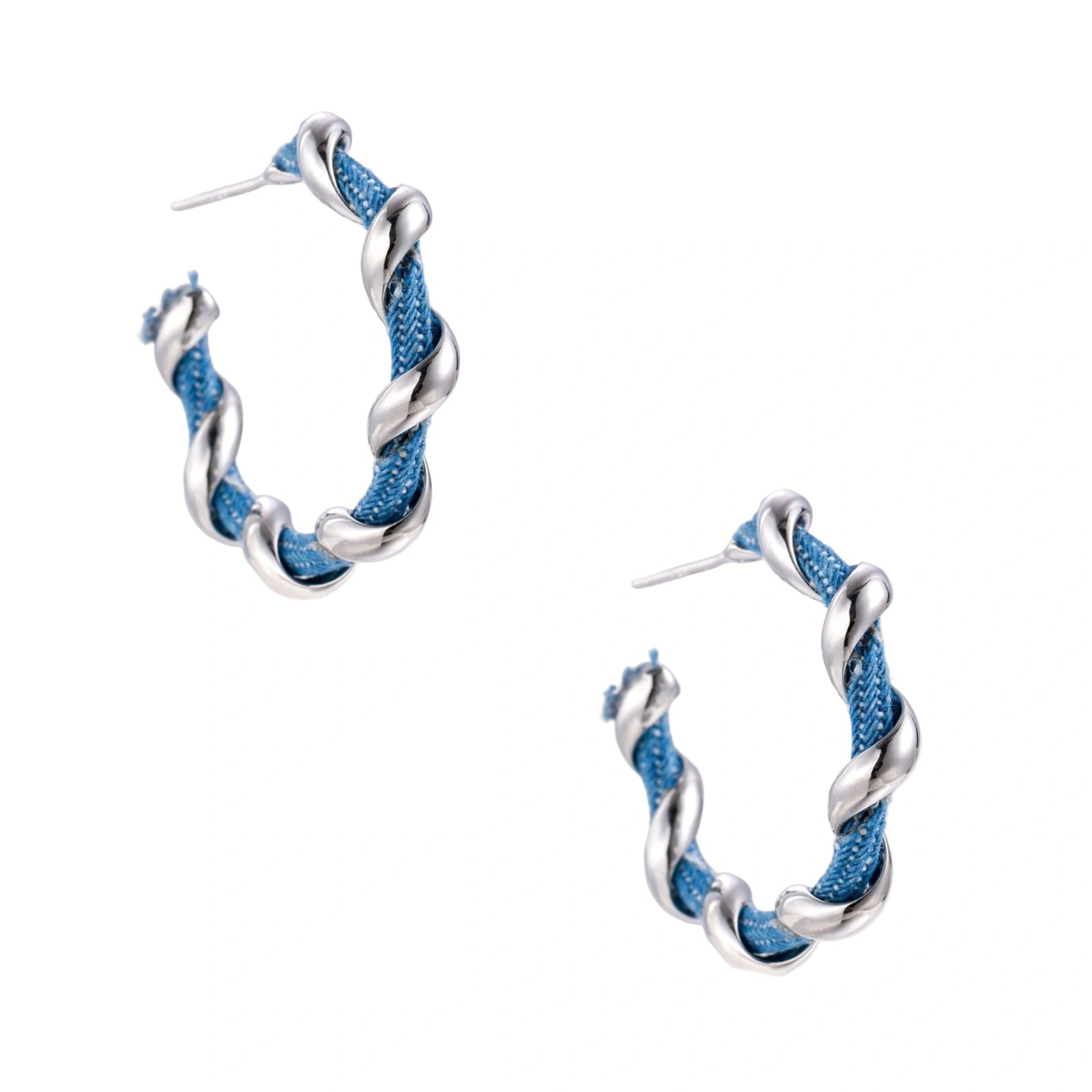 White gold-plated hoops intertwined with blue denim fabric in a twisted rope design on cream background.