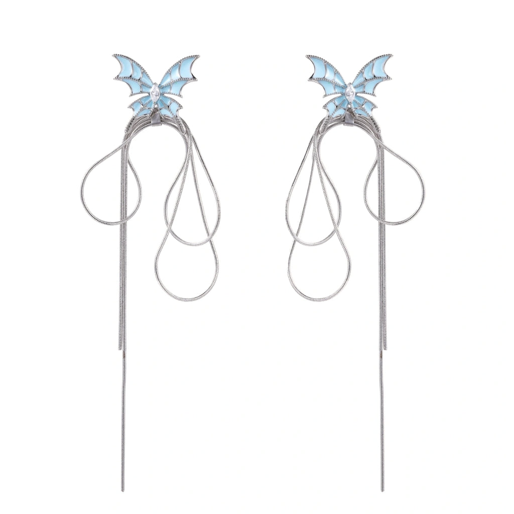 Long silver-tone earrings with powder blue enamel butterfly studs and flowing chain tassels on cream background