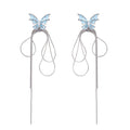 Long silver-tone earrings with powder blue enamel butterfly studs and flowing chain tassels on cream background