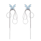 Long silver-tone earrings with powder blue enamel butterfly studs and flowing chain tassels on cream background