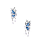 Silver butterfly earrings with blue denim fabric wings and dangling teardrop crystals on cream background