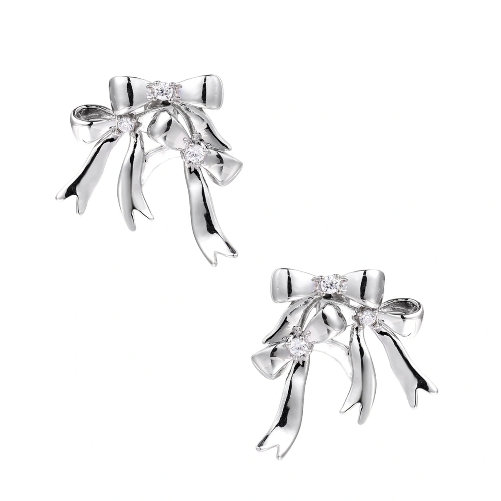 Sculptural bow earrings in polished white gold plate with sparkling zirconia stones and flowing ribbon details