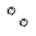 Pair of stud earrings with frayed blue denim petals around white pearl centers and silver prongs on cream background