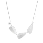 Minimalist sterling silver necklace with three brushed leaf-shaped pendants on delicate chain against white background