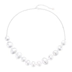 Graduated pearl-finish silver discs forming an organic bubble bib necklace on delicate chain against cream background.
