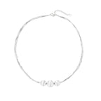 Sterling silver multi-strand necklace with three brushed round beads on cream background