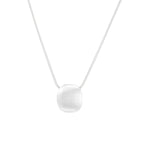 Minimalist brushed sterling silver dome pendant on delicate chain against cream background, showing matte textured finish