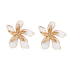 White enamel tropical flower earrings with sculptural gold-plated center and organic petal design on cream background