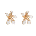 White enamel tropical flower earrings with sculptural gold-plated center and organic petal design on cream background