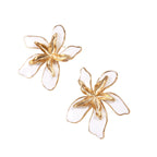 White enamel tropical flower earrings with sculptural gold-plated center and organic petal design on cream background