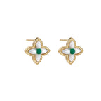 Gold quatrefoil stud earrings with white mother-of-pearl petals and emerald green gemstone center on beige background.