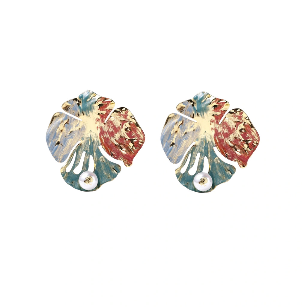 Artistic monstera-shaped earrings with teal, coral, and cream enamel brushstrokes, gold trim, and white pearl accent