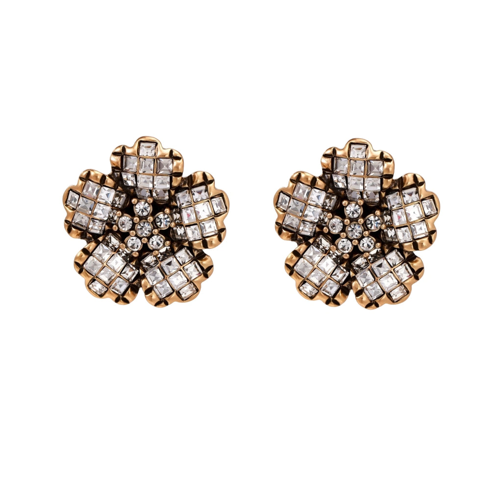 Gold-plated floral stud earrings with geometric zirconia crystals arranged in five-petal design on cream background