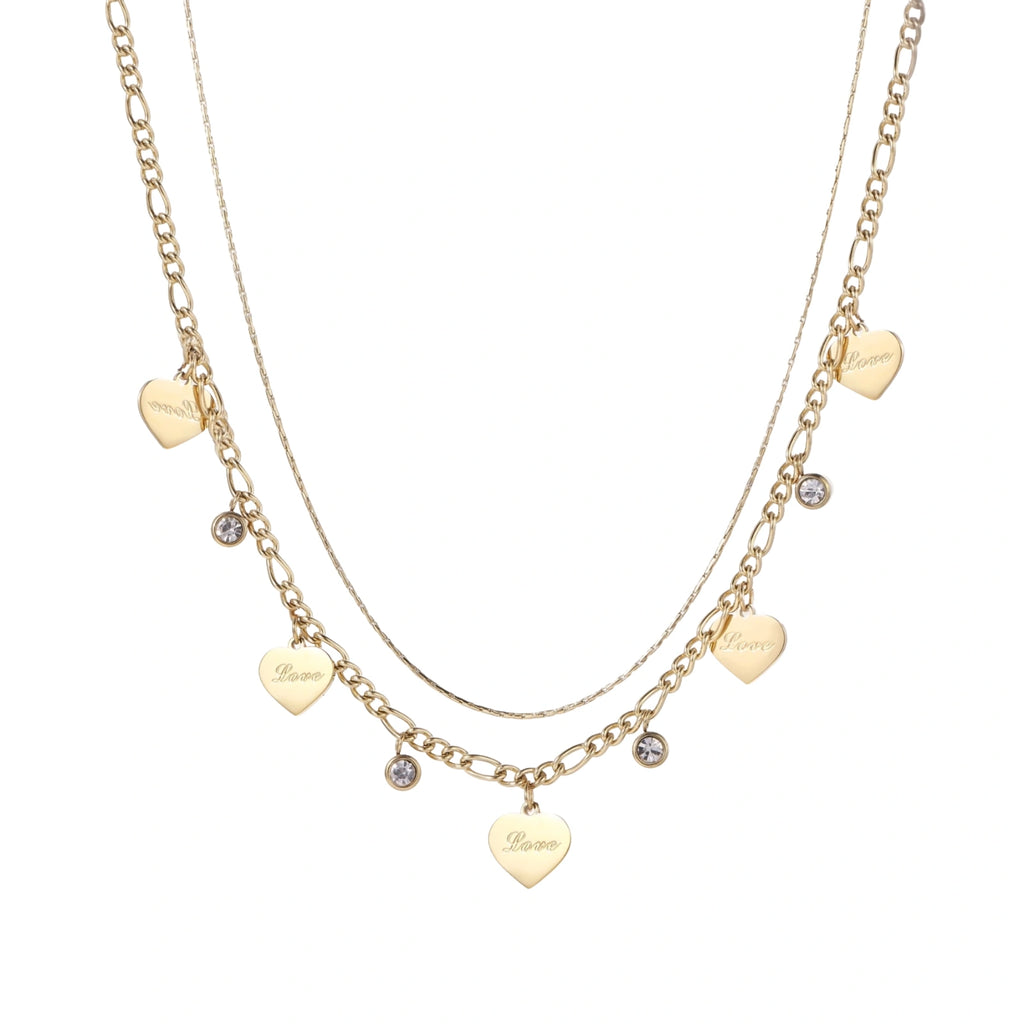 Gold layered necklace set with engraved heart pendants and crystal accents on cream background