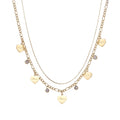 Gold layered necklace set with engraved heart pendants and crystal accents on cream background