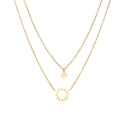 Gold layered necklace set with sunburst and smiley face pendants on delicate chains against white background.