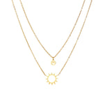 Gold layered necklace set with sunburst and smiley face pendants on delicate chains against white background.