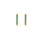 Pair of small gold huggie hoop earrings with bright green cubic zirconia stones on cream background