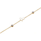 Gold chain bracelet with white mother of pearl butterfly pendant and two bezel-set crystals on cream background