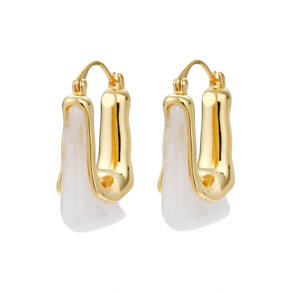 Sculptural gold-plated hoop earrings with flowing curved design and lever-back closure on cream background.