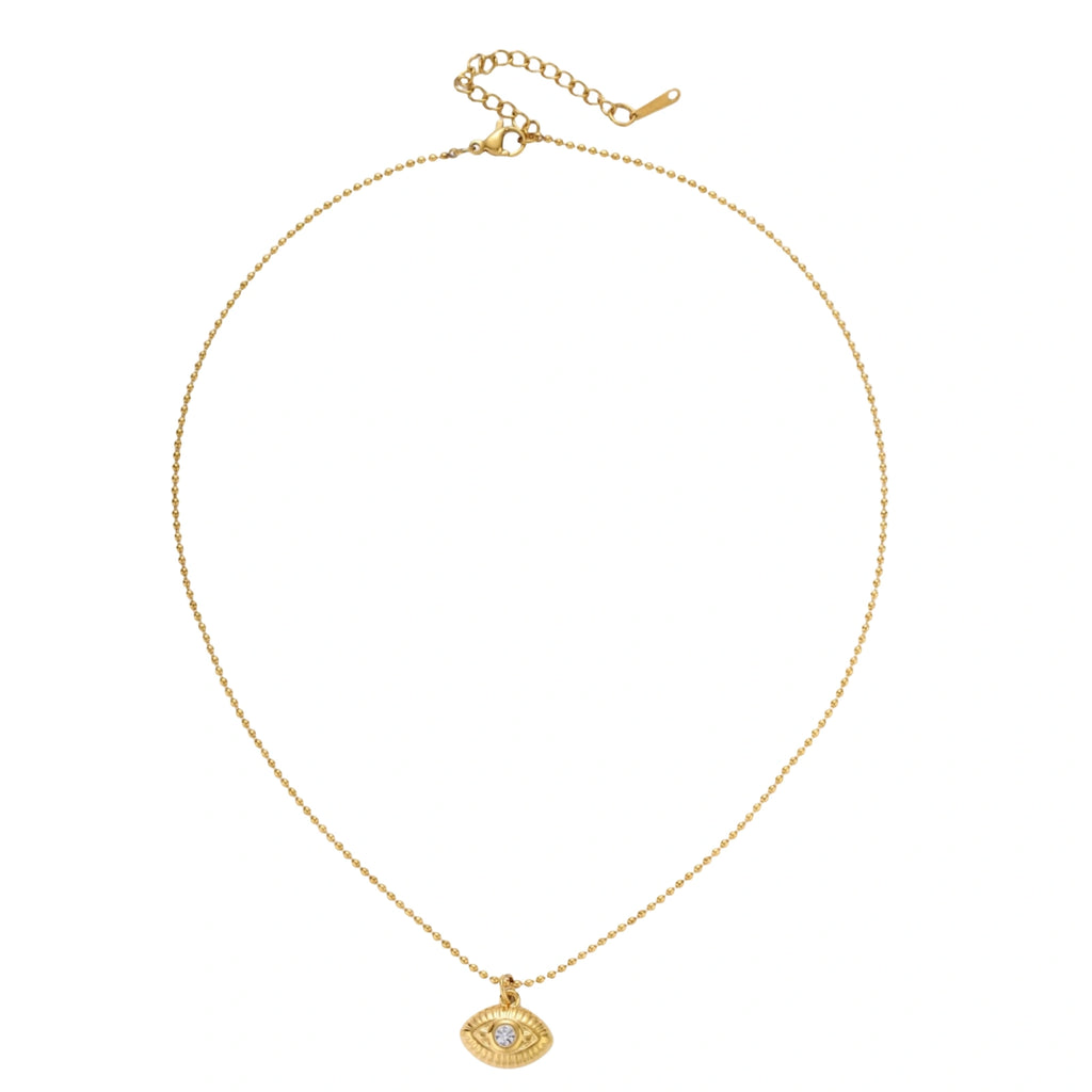 Layered necklace with green stone beads, gold spacers, white accents, and protective eye pendant on cream background.