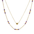 Two layered gold-tone necklaces with purple stone beads and star pendant against cream background.