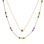 Two layered gold-tone necklaces with purple stone beads and star pendant against cream background.