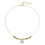 Gold-toned beaded necklace with grey stones and quatrefoil abalone shell pendant on cream background.