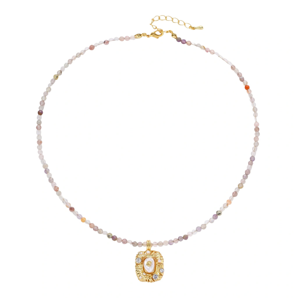 Ornate gold-plated pendant necklace with multicolored gemstone beads in purple, pink and clear tones on white background