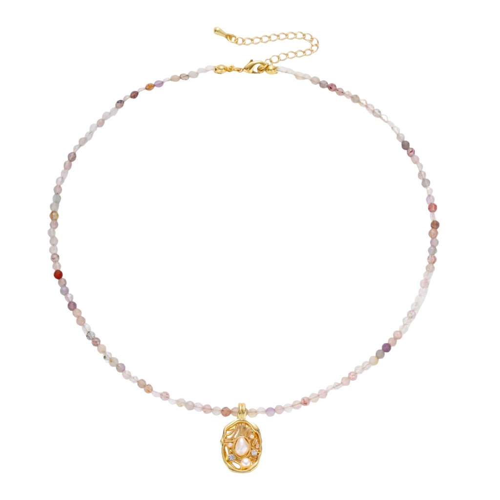 Delicate gold-plated necklace with mixed gemstone beads and ornate oval pendant on white background