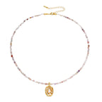 Delicate gold-plated necklace with mixed gemstone beads and ornate oval pendant on white background