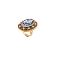 Gold-plated ring with oval blue floral cameo, pearl accents, and black enamel detailing on white background.