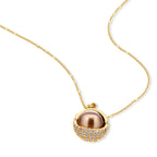Elegant spherical pendant necklace and earrings set featuring crystal-pavé bottom half in gold or silver finish on white background.