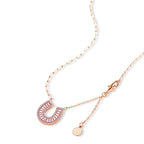 Sparkling horseshoe-shaped jewelry set with AAA cubic zirconia in gold-plated and white gold finishes on cream background.